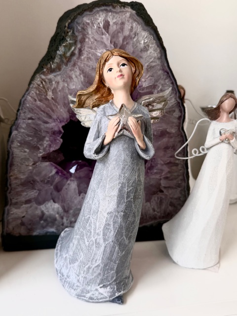 Anděl stojící s hvězdou a stříbrnými křídly